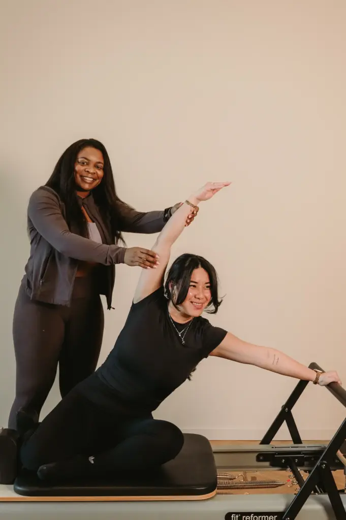 Instructor assisting client with stretch on reformer Pilates machine at Zen Zest Goes