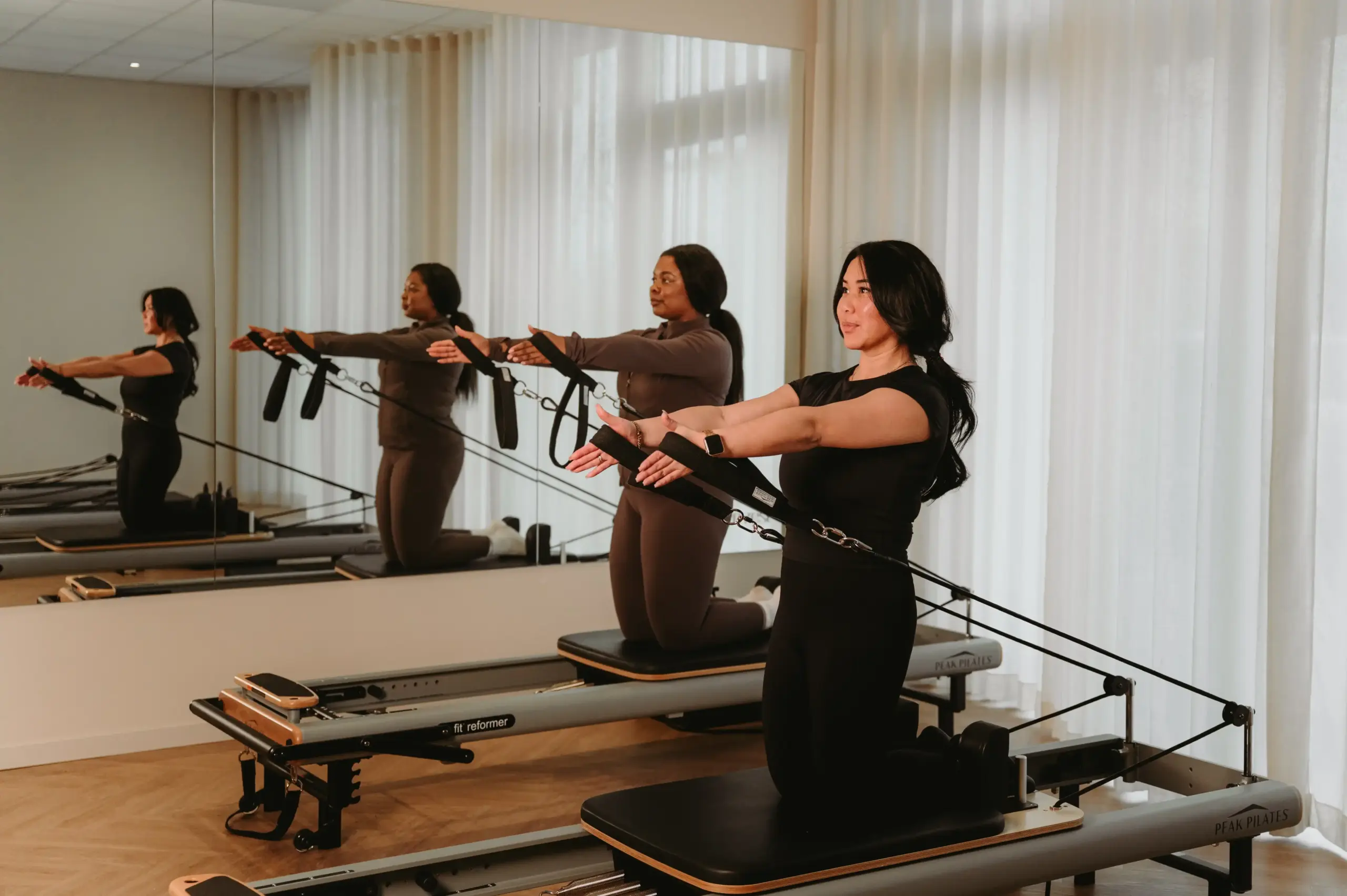 Reformer Pilates arm exercise in boutique studio Zen Zest Goes with mirror reflection