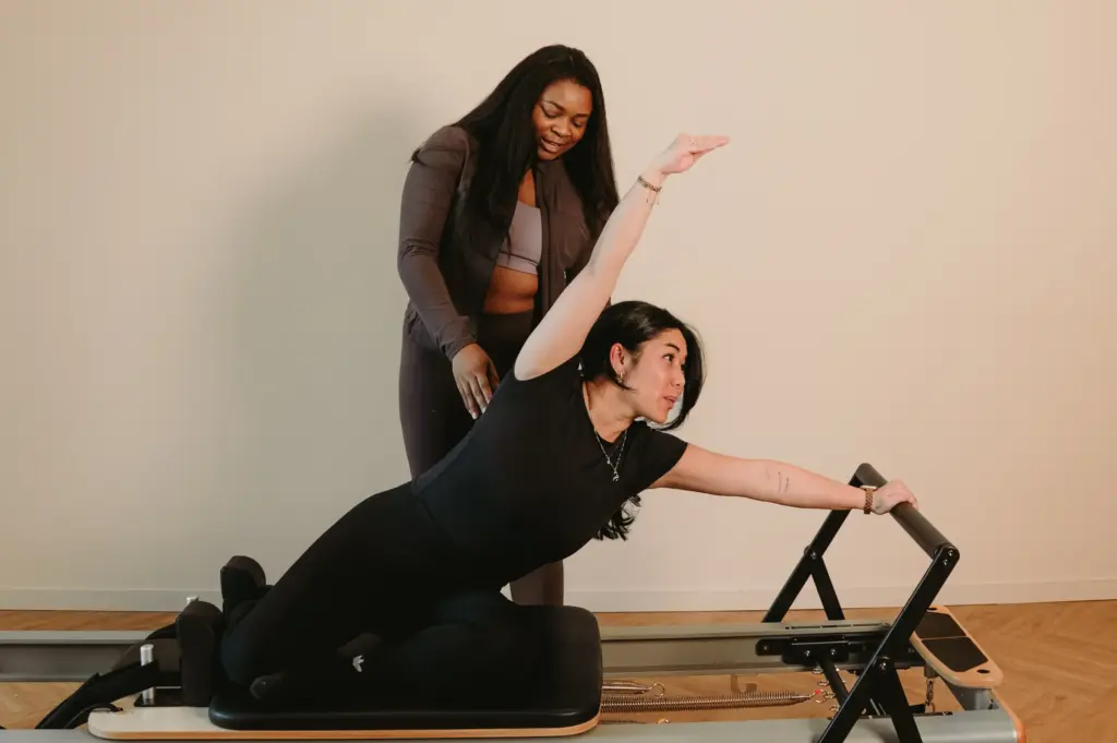 Reformer Pilates session with instructor assisting client in Zen Zest studio Goes